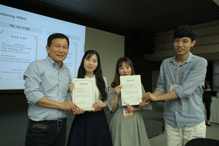CJ CGV '리버스 멘토링' 오리엔테션에 참가자들이 서약서를 들고 포토그레퍼 앞에서 포즈를 취하고 있다