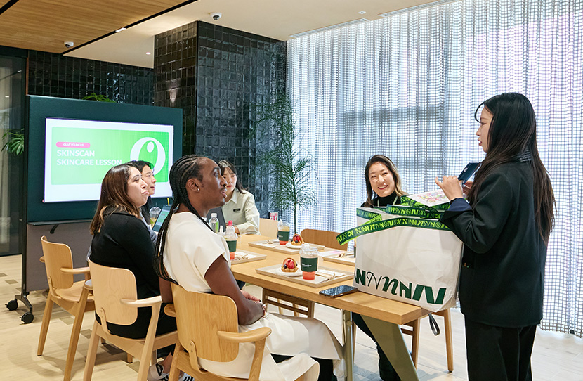 미국 매장 SM, ASM들이 서울 올리브영N 성수에서 교육 담당자로부터 웰컴 기프트를 전달받고 있다.