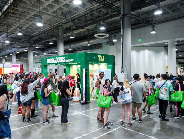 260818 CJ푸드빌 [사진1]KCON LA 2026 방문객들이 현지시간으로 15일 CJ올리브영 타포린백을 메고 CJ푸드빌의 뚜레쥬르 이벤트를 참여하기 위해 줄을 서있다(제공 CJ ENM)
