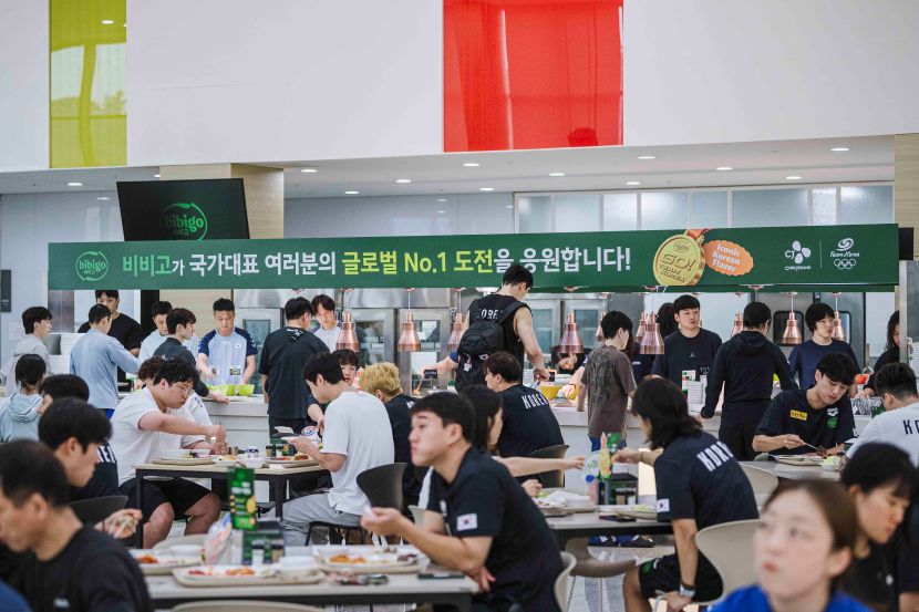 '비비고가 국가대표 여러분의 글로벌 No.1 도전을 응원합니다!' 현수막과, 식사하는 선수단의 모습